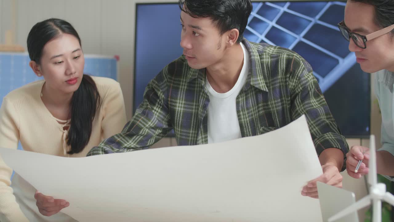 태양 전지 패널 집 모델과 함께 아시아 엔지니어 그룹의 클로즈업은 사무실에서 블루프린트 작업에 대해 논의합니다.