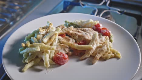 pollo cursi y pasta con tomates cherry servidos en un plato