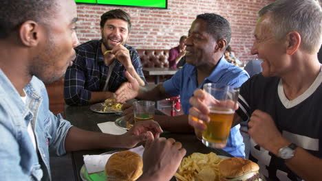 Grupo-De-Amigos-Varones-Comiendo-En-El-Bar-De-Deportes-Rodada-En-R3d