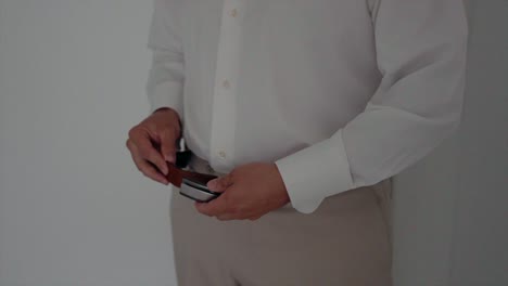 man in a white shirt and beige pants adjusting his belt