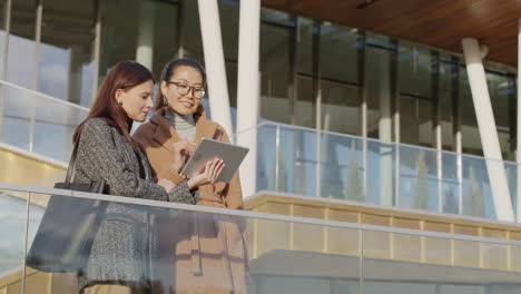 two businesswomen collaborating on a digital tablet outdoors