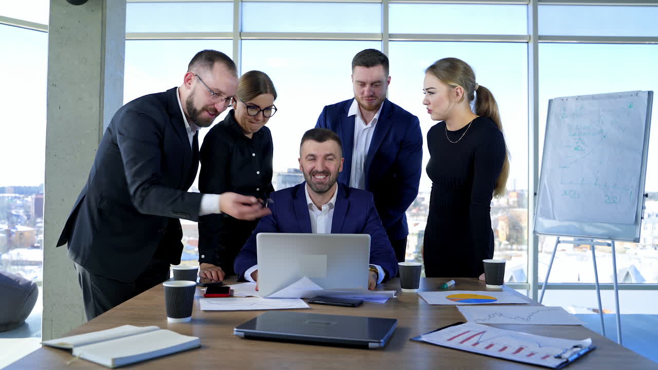 Teamwork of businessmen. Group of entrepreneurs in elegant clothes work together on a project in front of a laptop in office centre.