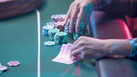 person handling poker chips and cards on a green gaming mat