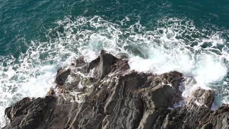 Top-down-aerial-view-of-waves-crashing-on-rocky-shoreline