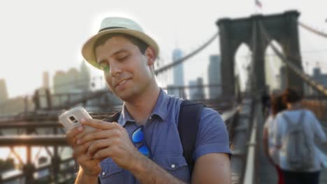 man using smartphone on brooklyn bridge, new york city