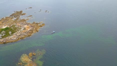 Fishing-Boat-Going-Out-To-Sea-Past-Rocky-Outcrop-In-Galicia