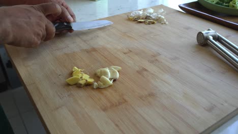 slicing fresh ginger and garlic on a cutting board