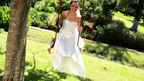 Smiling-bride-sitting-on-a-swing-looking-at-camera