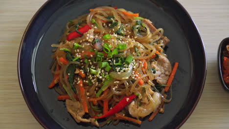 japchae or stir-fried korean vermicelli noodles with vegetables and pork topped with white sesame - korean traditional food style