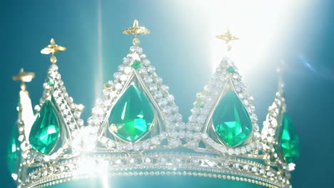 close up of a golden crown with green emerald gemstones