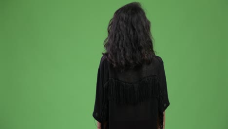 vista trasera de una mujer joven con cabello largo y ondulado pensando y esperando