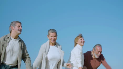 excited senior couples jumping up in background of blue sky