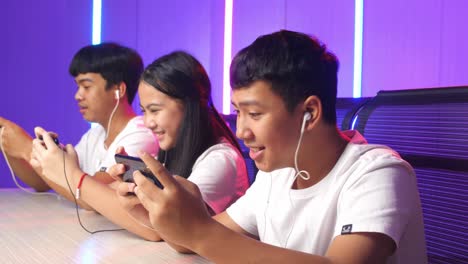 team of asian esport gamers playing in competitive video games on a cyber games tournament by mobile phone and celebrate win