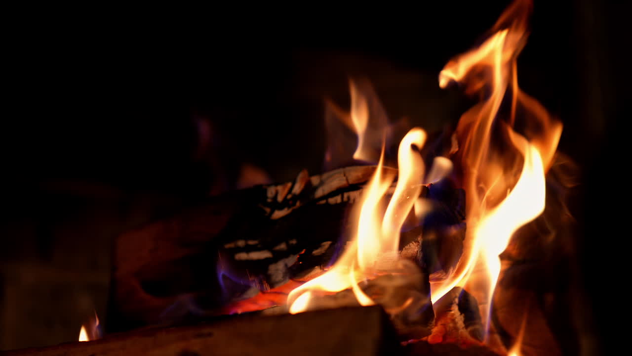Bright fire on dark background. Wooden logs burning in beautiful vivid fire in fireplace. Warm cozy fire in a fireplace. Close-up.