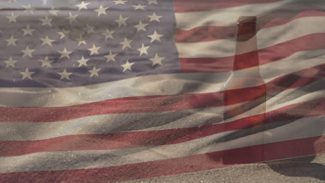 Beer-bottle-in-sand-with-US-flag-waving-foreground