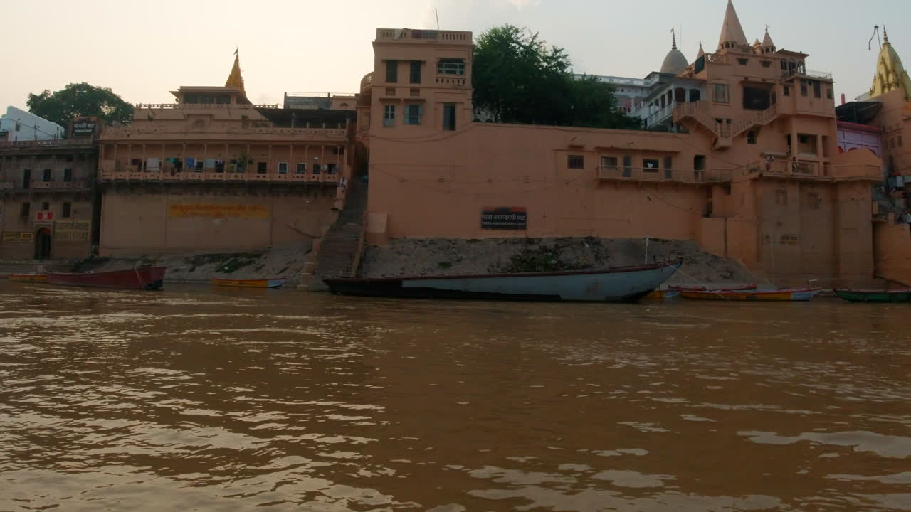 cinematográfica puesta de sol panorámica antigua ciudad santa varanasi india río ganges canal crucero en barco estado del norte gente en la provincia de ghat pradesh paisaje gris nublado a la derecha seguir el movimiento