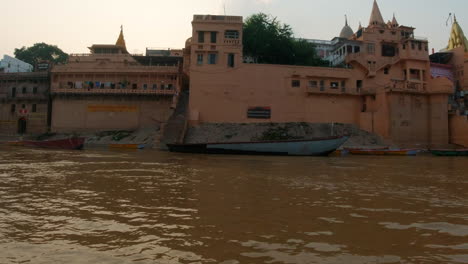 Cinematic-sunset-scenic-Ancient-Holy-city-Varanasi-India-Ganges-River-canal-boat-cruise-Northern-State-people-at-Ghat-Pradesh-Province-landscape-gray-cloudy-right-follow-motion