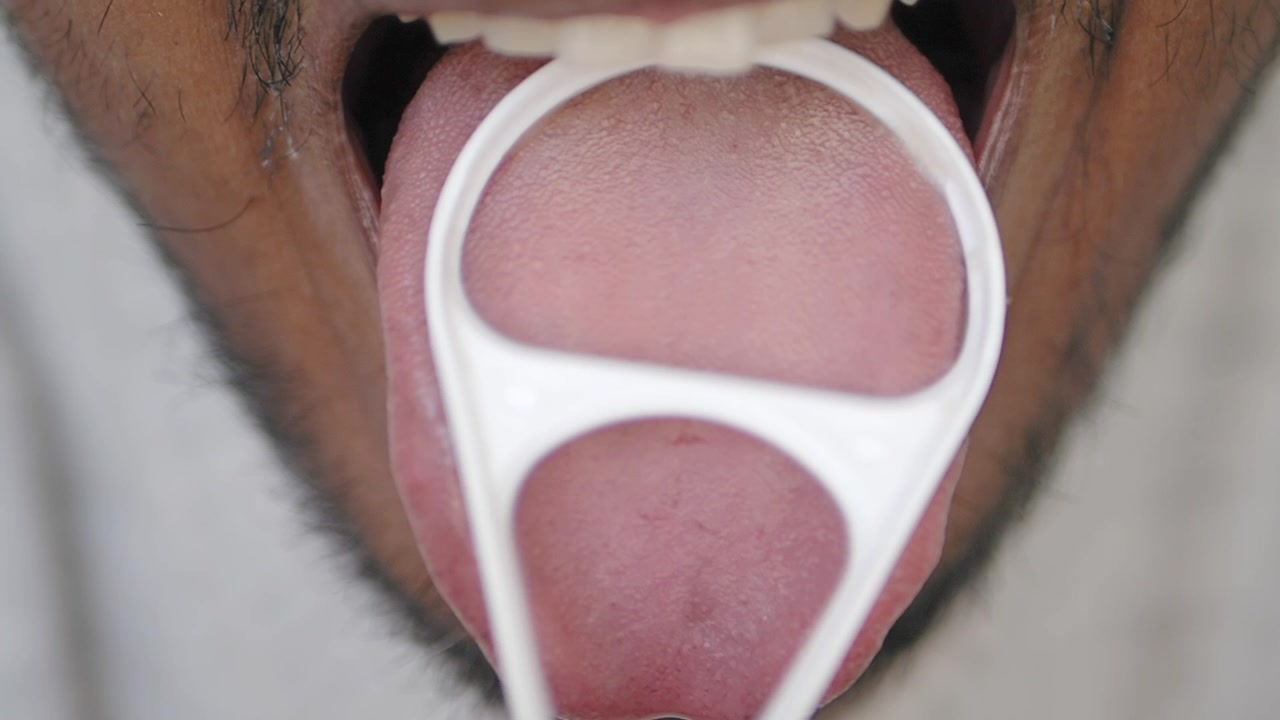 Close-up of a Person Cleaning Their Tongue with a Tongue Scraper