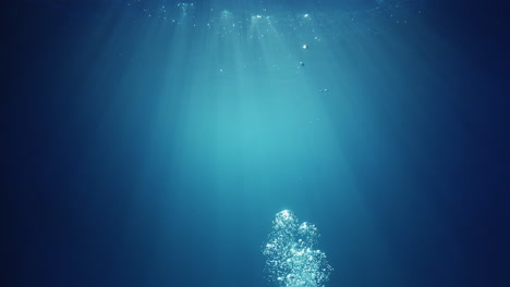 underwater sunlight beams shining from above coming through the deep crystal clear blue water causing a beautiful water lighting reflections curtain with air bubbles rising up to the surface