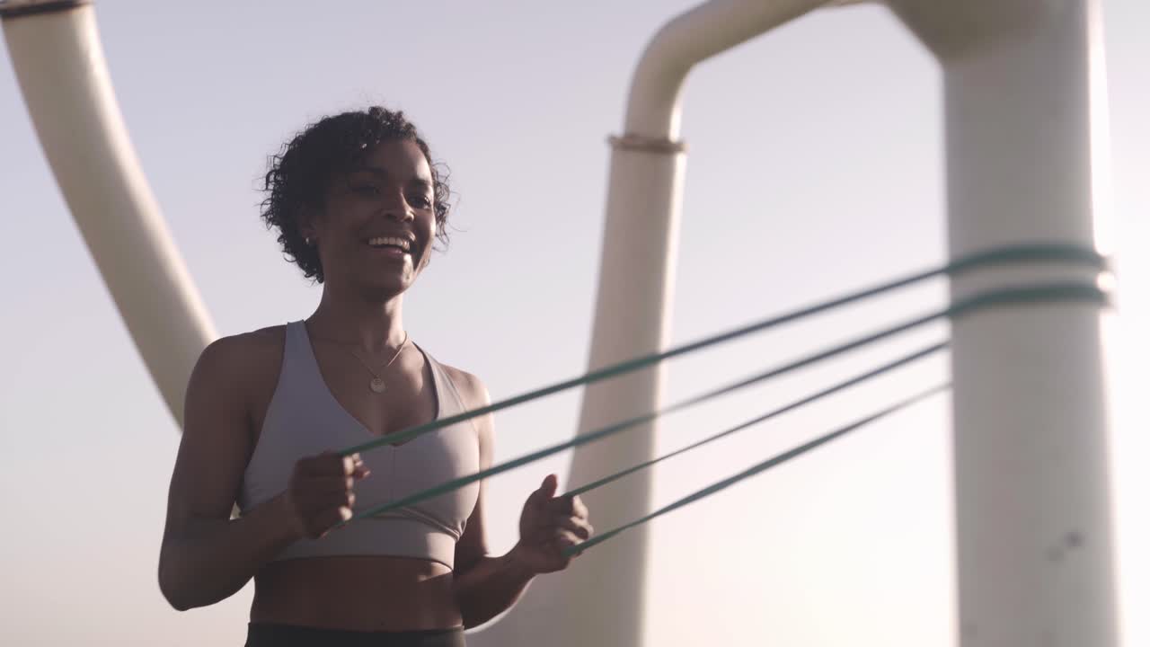 Mulher afro-americana saudável treina com faixa de resistência ao ar livre.