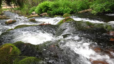 Wide-high-angle-shot-of-downstream-from-Njupeskärs-waterfall-descending-rocky-steps-between-green-forest-in-Fulufjällets-National-park,-in-Sweden