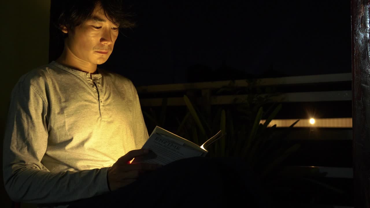 lado en la foto de un hombre inteligente leyendo un libro iluminado por una pequeña luz en la noche antes de acostarse