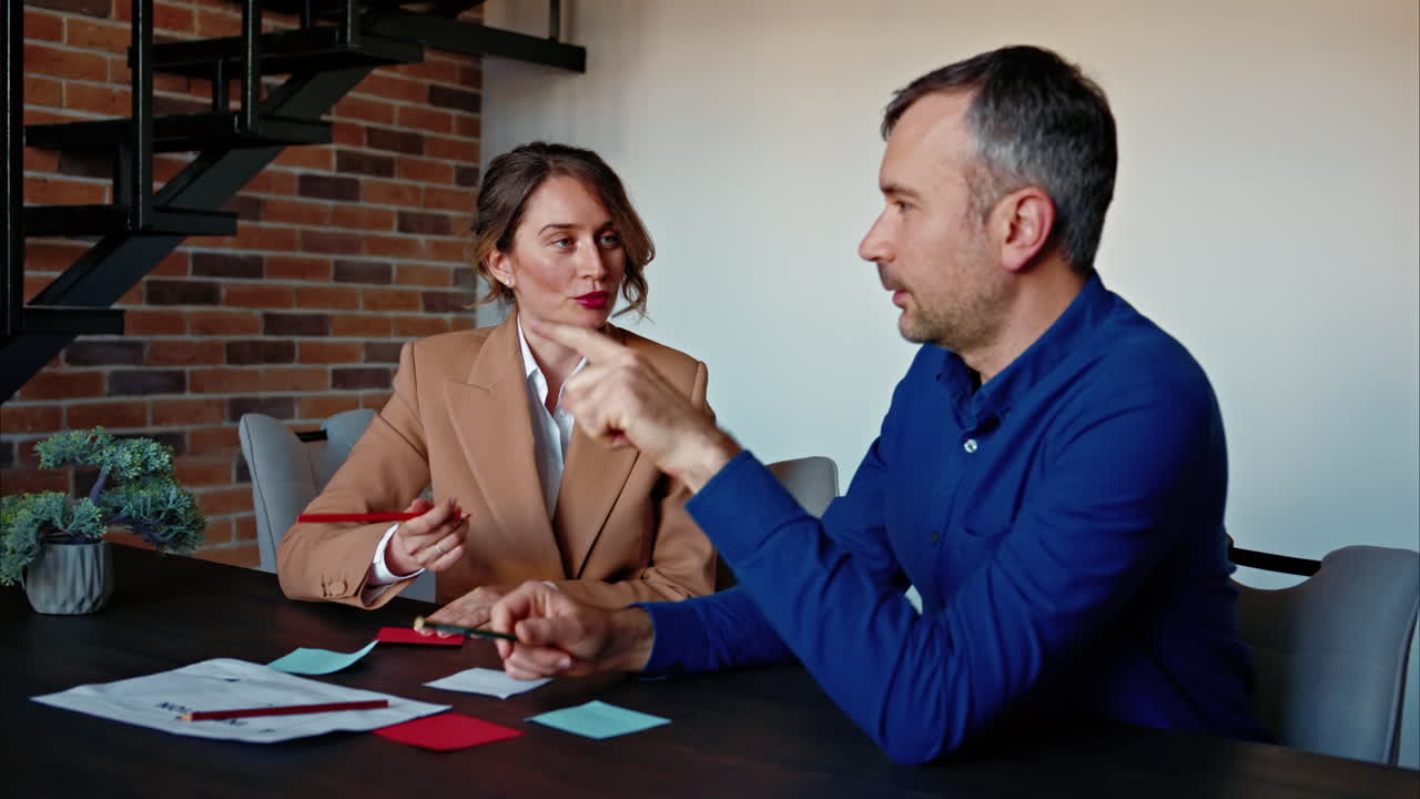 Man and woman discussing plans at the table, in an office