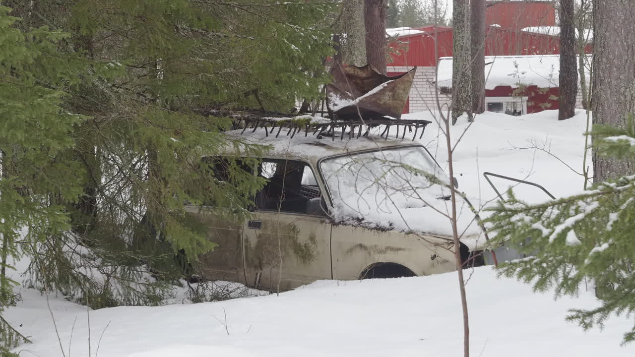 Old Snow-Covered Abandoned Car Between Trees in Urban Area in Lapland