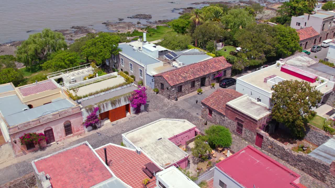 vista aérea del carro en calles empedradas con flores y árboles abundantes con la arquitectura antigua y representativa de la colonia del sacramento, uruguay