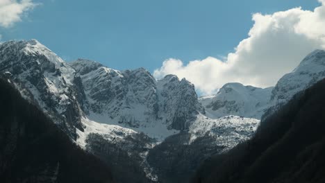 Thick-white-clouds-flowing-over-snow-covered-mountain-tops,-timelapse