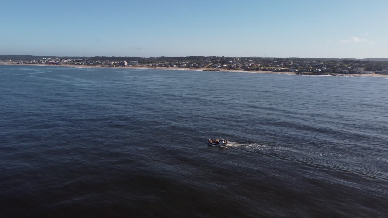 Fiskebåd navigerer på Atlanterhavet med Uruguays kystlinje i baggrunden