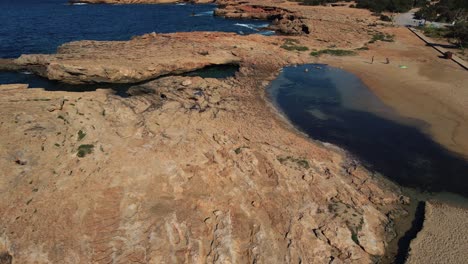 Aerial-Flying-Over-Cala-Bassa-Rocky-Coastline-With-Blue-Sea-Waves-In-Ibiza