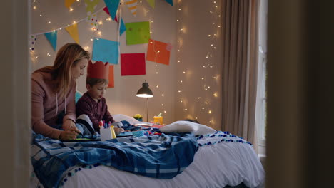 niño pequeño haciendo invitaciones para la fiesta de cumpleaños con la madre ayudando al hijo en el dormitorio colorido disfrutando de la imaginación creativa