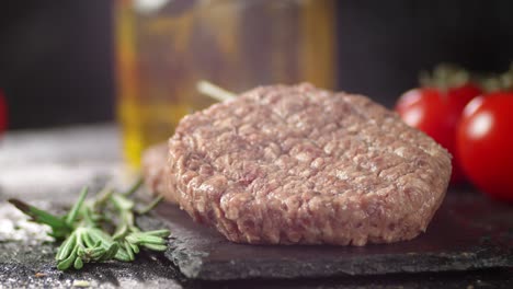 raw burger of fresh meat rotates on a stone board.