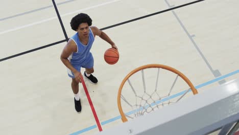 high angle of african american male basketball player shooting ball at hoop on court, slow motion