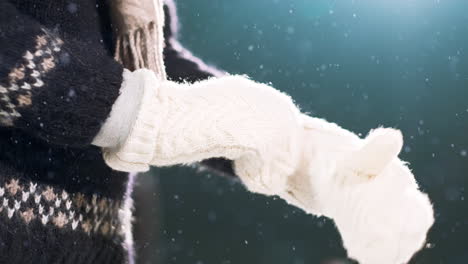 close up of young norwegian female hands puts on warm white gloves as snow falls gently on the clothes and ground on a cold freezing winters day at the ice skating rink christmas break activity