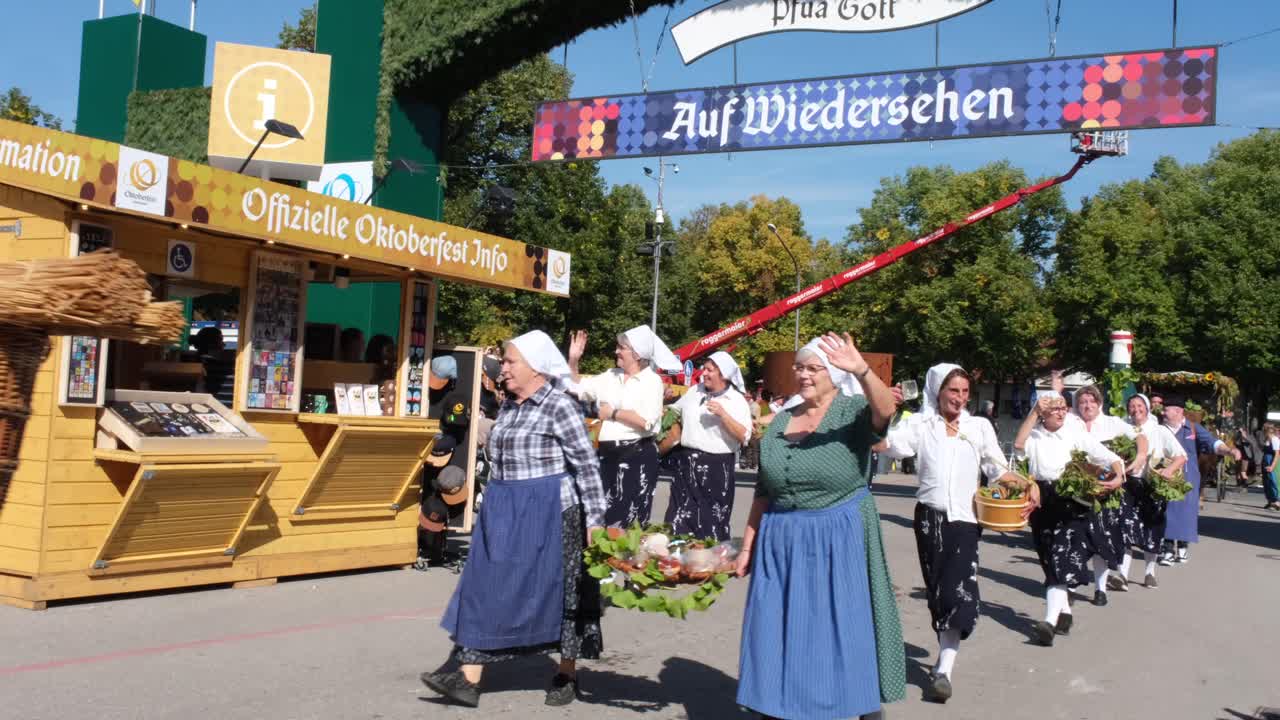 Matured men and women, dressed in traditional farmer-like attire, enter the Oktoberfest area, exuding a rustic charm as they join the lively celebration.