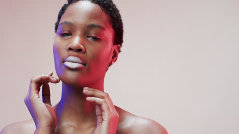 african american woman with short dark hair in blue and pink light with copy space, slow motion