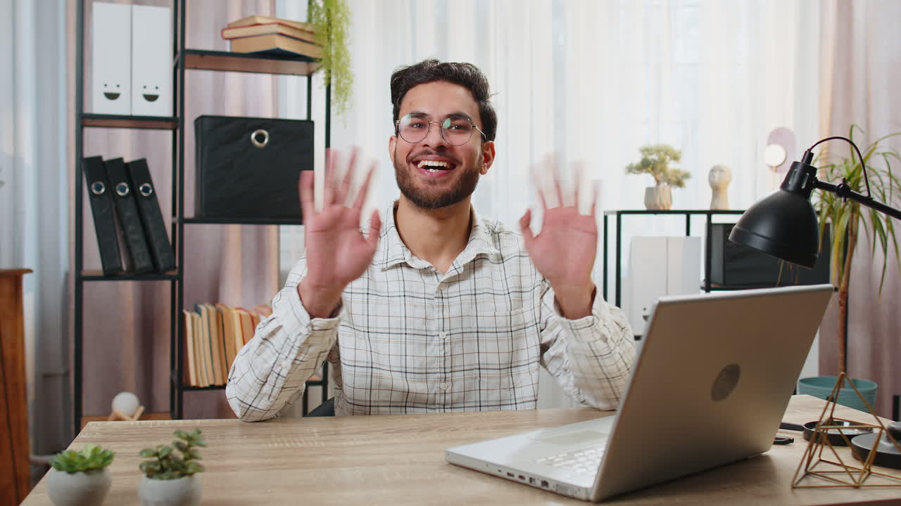 Un uomo d'affari indiano saluta con la mano e dà il benvenuto a qualcuno in una conversazione di webinar online