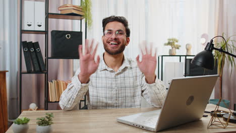 Indian business man employee waves hand hi greeting welcomes someone online webinar conversation