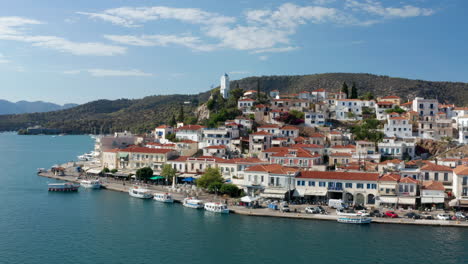 Vista-Panorámica-De-Los-Edificios-Y-La-Torre-Del-Reloj-En-La-Isla-De-Poros-En-Verano-En-Grecia,-Amplia-Antena