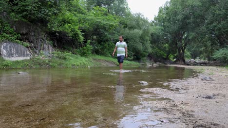 isolated man walking in natural river stream during morning
