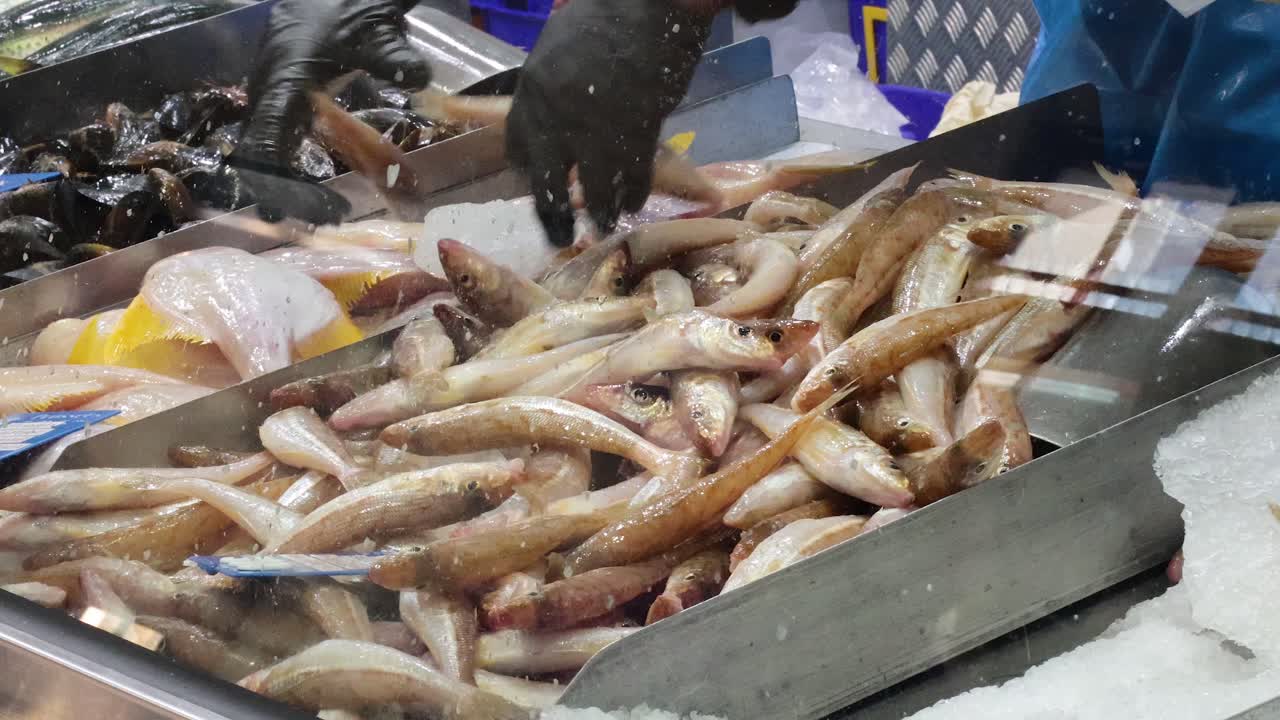 trabajador clasificando pescado en el puesto del mercado