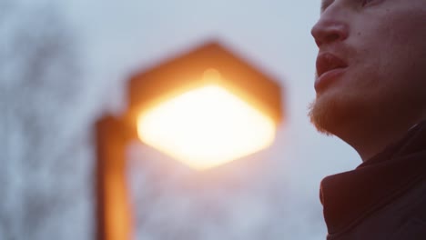 Man-standing-under-park-light-then-slowly-walking-away