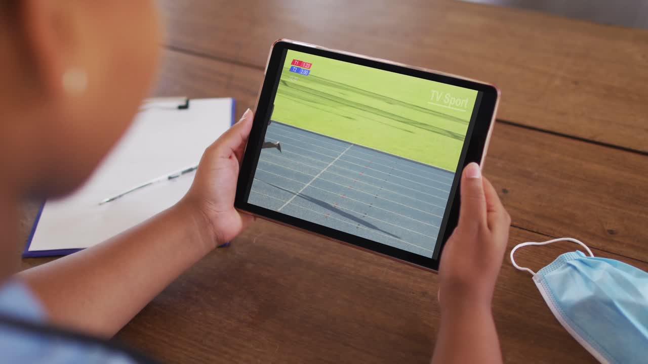 compuesto de una mujer en el sofá en casa viendo atletismo corriendo evento en la tableta