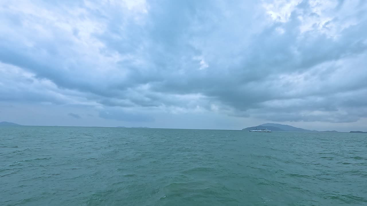 Overcast skies and choppy waters create a dramatic seascape at Koh Samui. The horizon reveals distant islands under a moody atmosphere