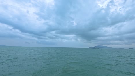 overcast skies and choppy waters create a dramatic seascape at koh samui. the horizon reveals distant islands under a moody atmosphere