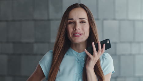 mujer de negocios sonriente grabando un mensaje de voz en un teléfono inteligente en la ciudad