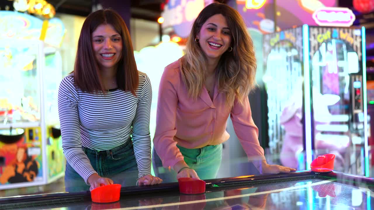 Dos mujeres jugando al air hockey en una sala de juegos