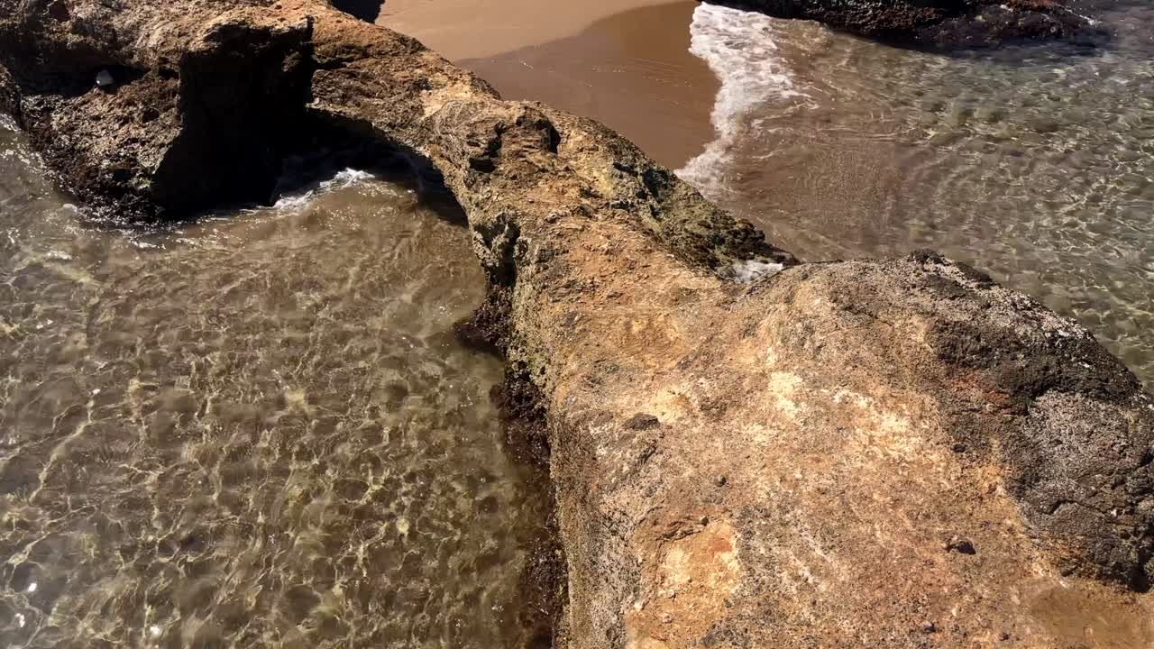 Piccola grotta rocciosa vicino ad acque cristalline su una spiaggia sabbiosa a Creta, Grecia